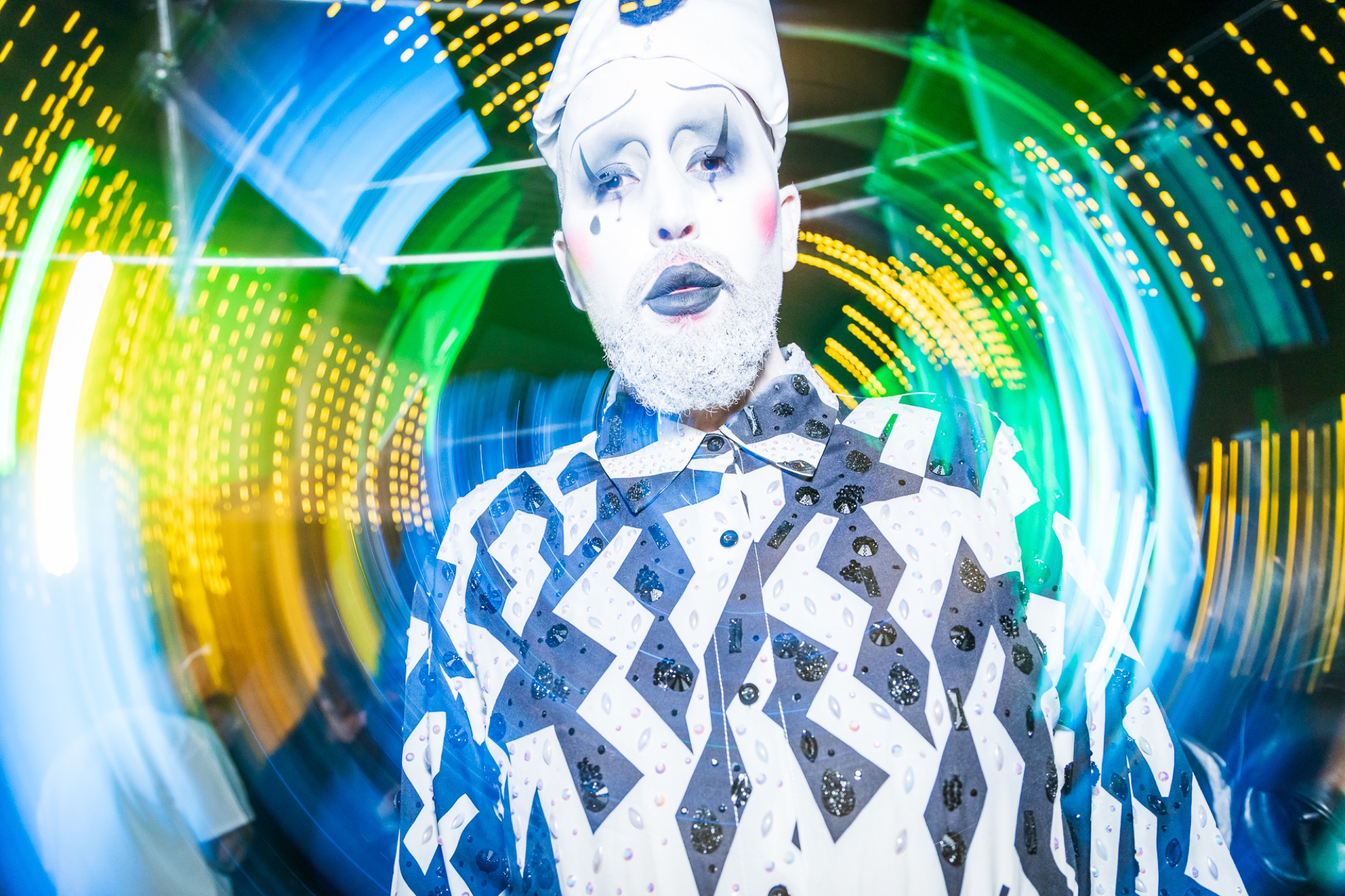 A drag performer in bold monochrome costume mid-performance under swirling club lights at Connections Nightclub, Perth